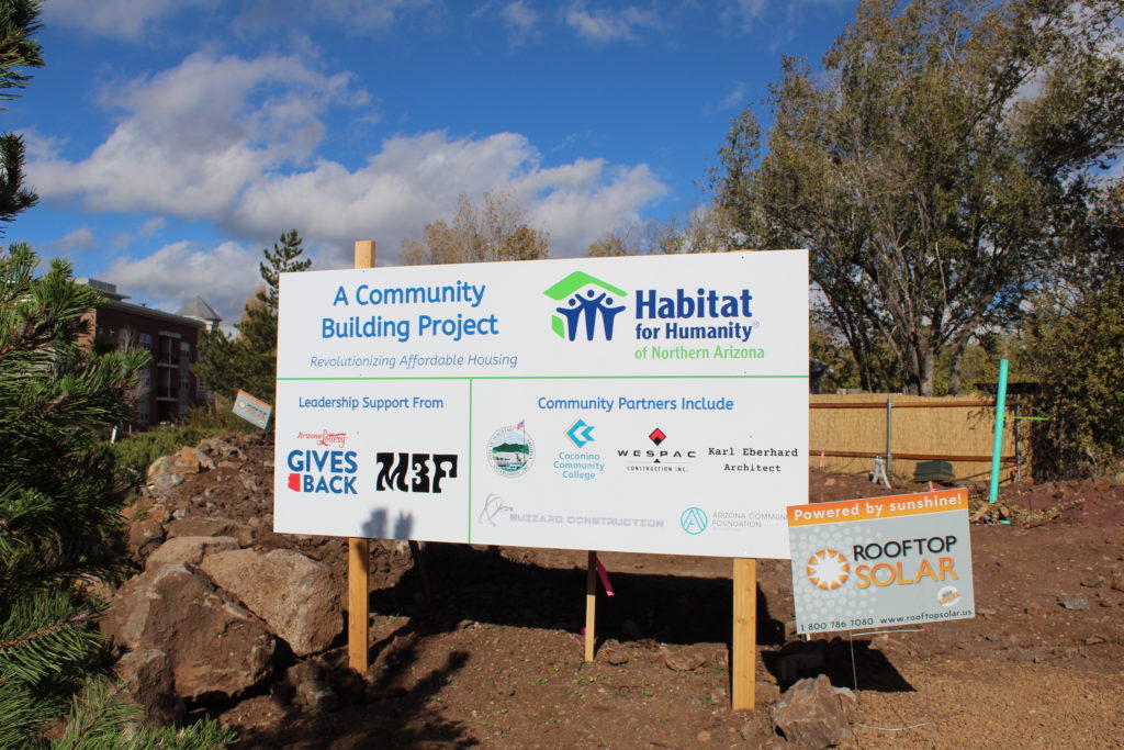 Rooftop Solar along with other partner signs next to new Habitat for Humanity house