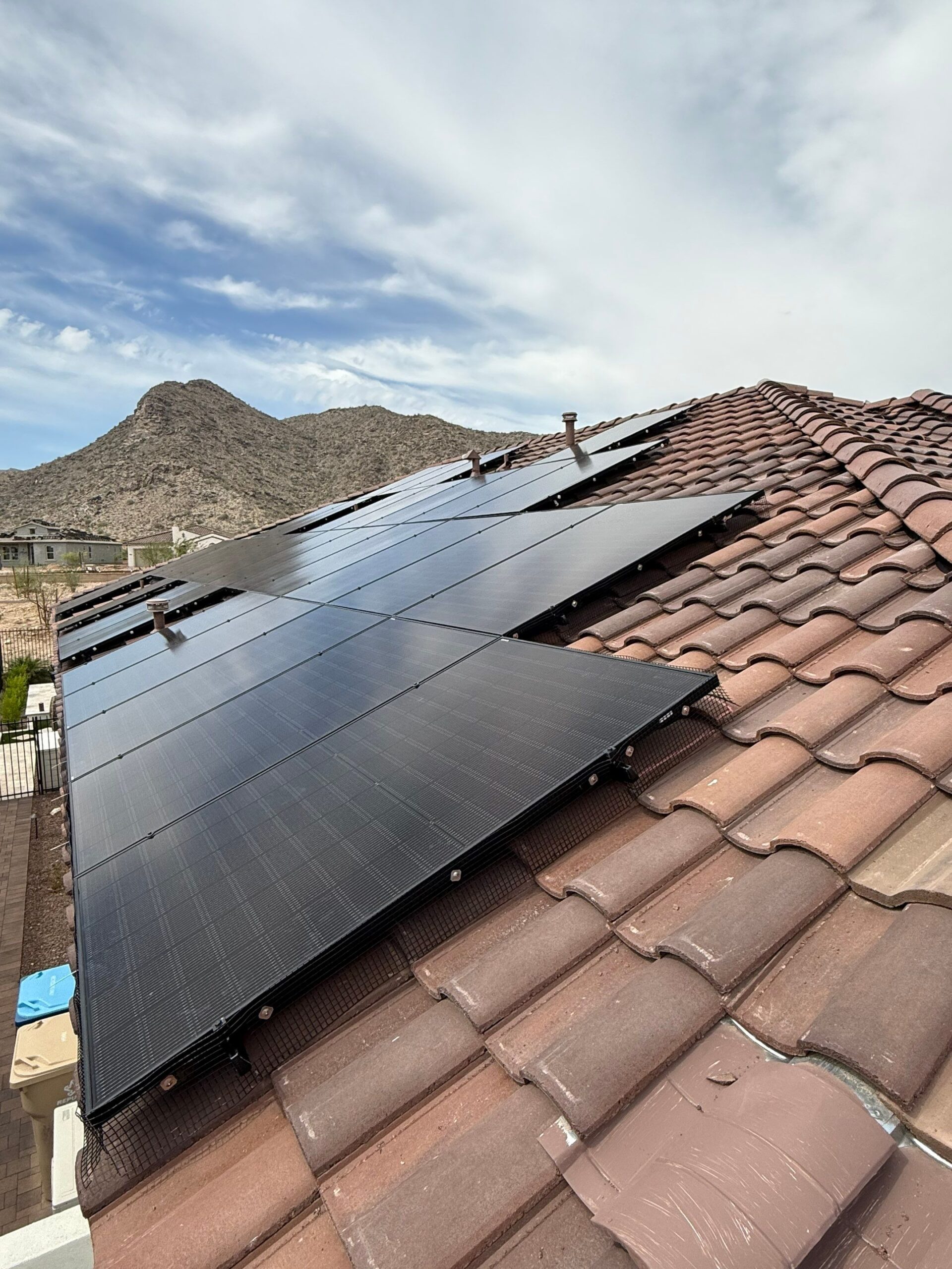 Jinko solar panels on a concrete tile roof in Buckeye, AZ, with a desert mountain behind the home
