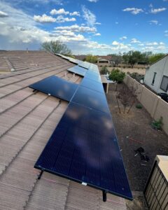 Long row of black Silfab solar panels along the edge of a tile roof above a Peoria, AZ backyard
