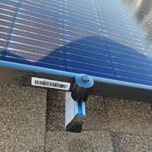 Close-up of a black clamp securing a solar panel frame to its mounting rail on a Sun City West, AZ, roof